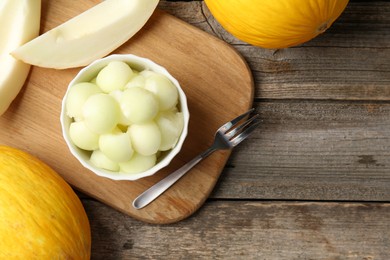 Photo of Melon balls in bowl and fresh fruits on wooden table, flat lay. Space for text