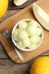 Photo of Melon balls in bowl and fresh fruits on wooden table, flat lay