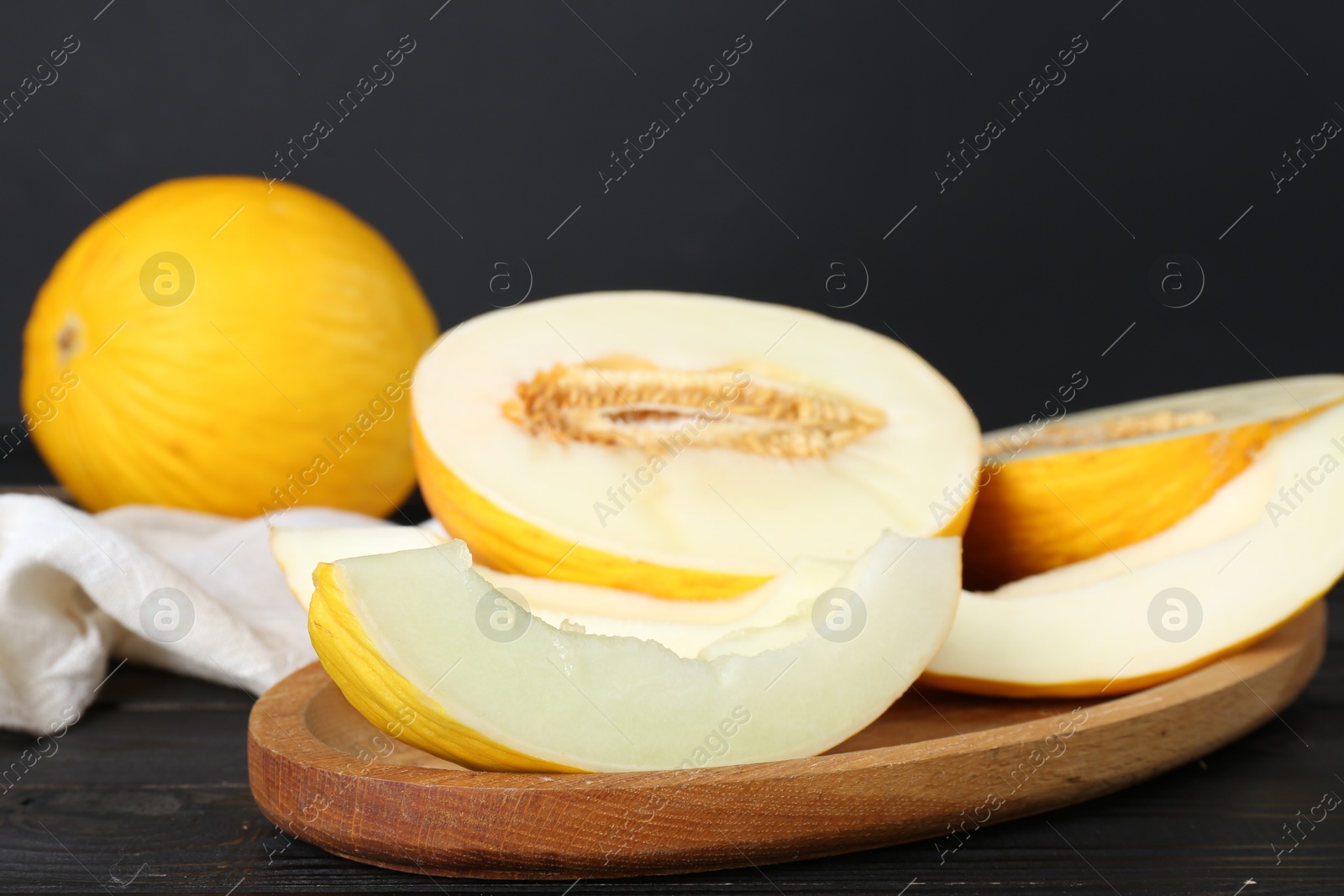 Photo of Fresh ripe melons on wooden table against black background