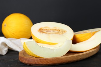 Fresh ripe melons on wooden table against black background