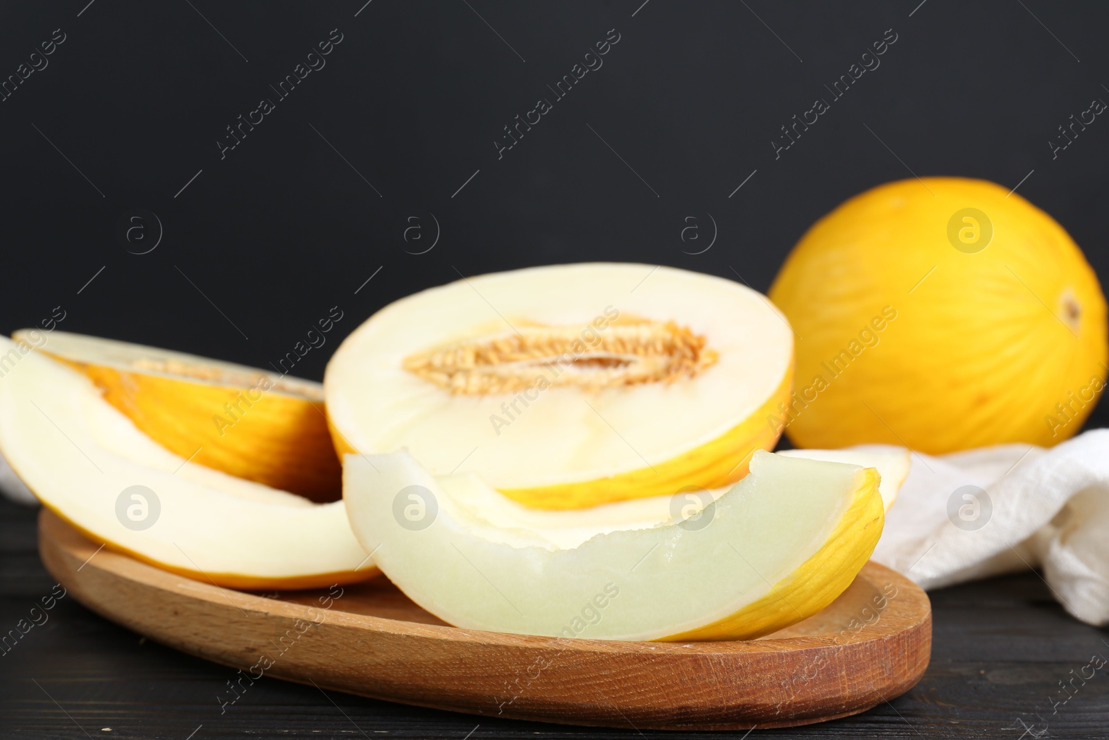 Photo of Fresh ripe melons on wooden table against black background