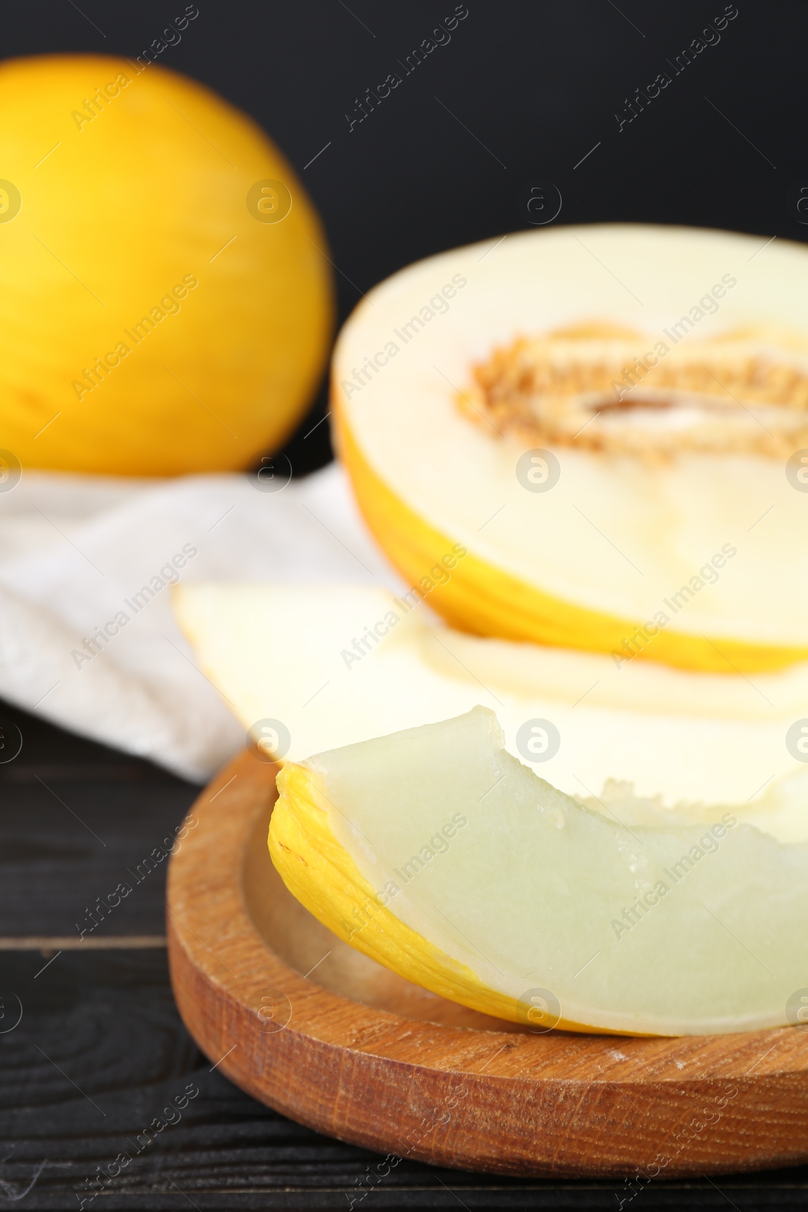 Photo of Fresh ripe melons on black wooden table, closeup