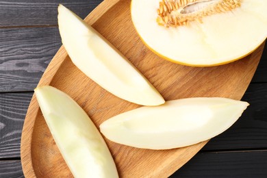 Cut fresh ripe melon on black wooden table, top view