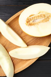 Cut fresh ripe melon on black wooden table, top view