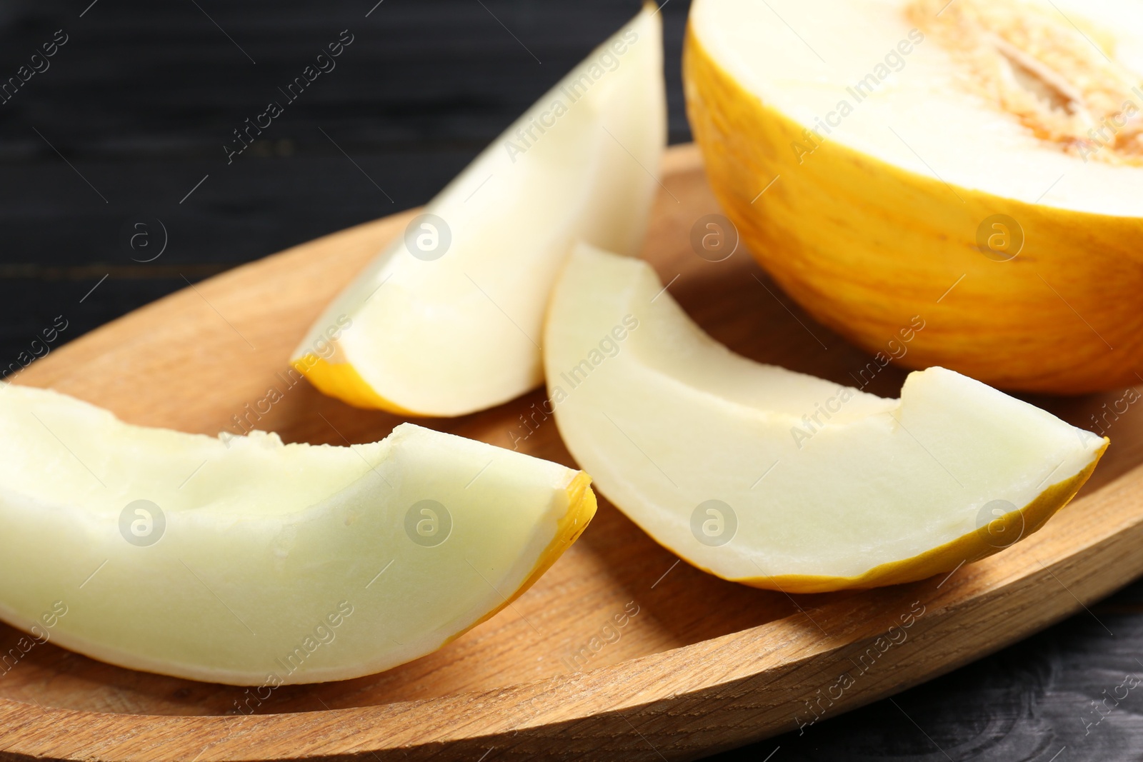 Photo of Cut fresh ripe melon on black wooden table, closeup