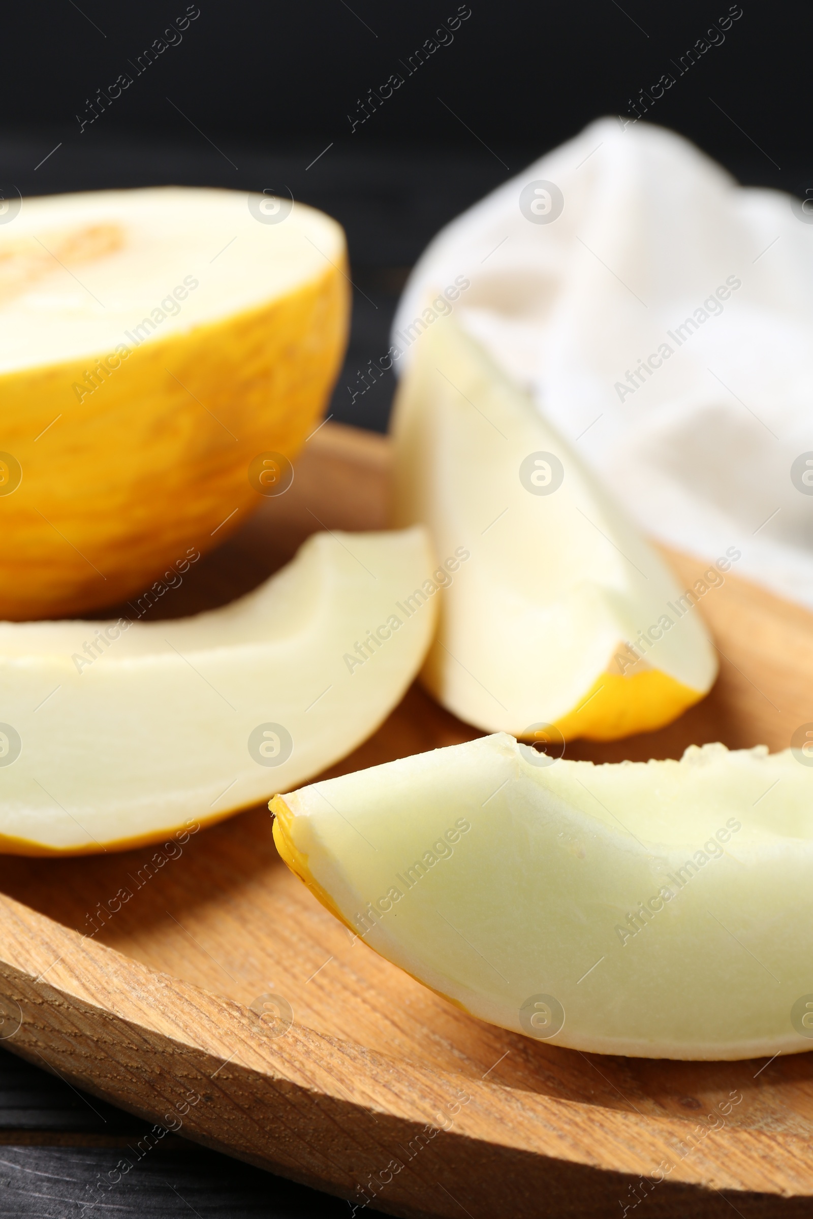 Photo of Cut fresh ripe melon on black wooden table, closeup