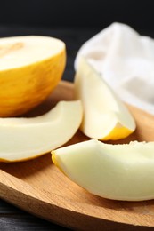 Photo of Cut fresh ripe melon on black wooden table, closeup