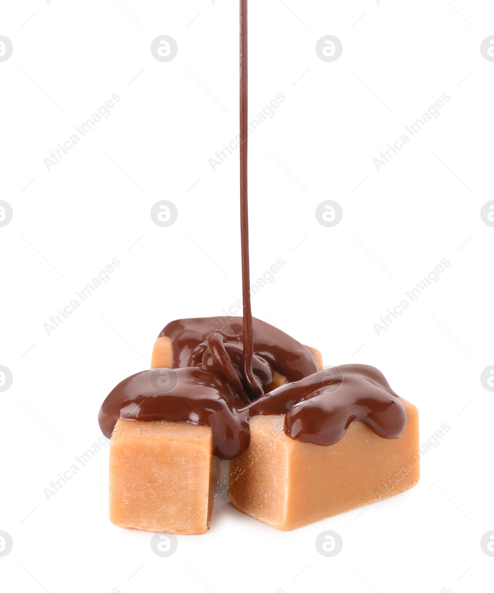 Photo of Pouring tasty melted chocolate onto caramel candies on white background