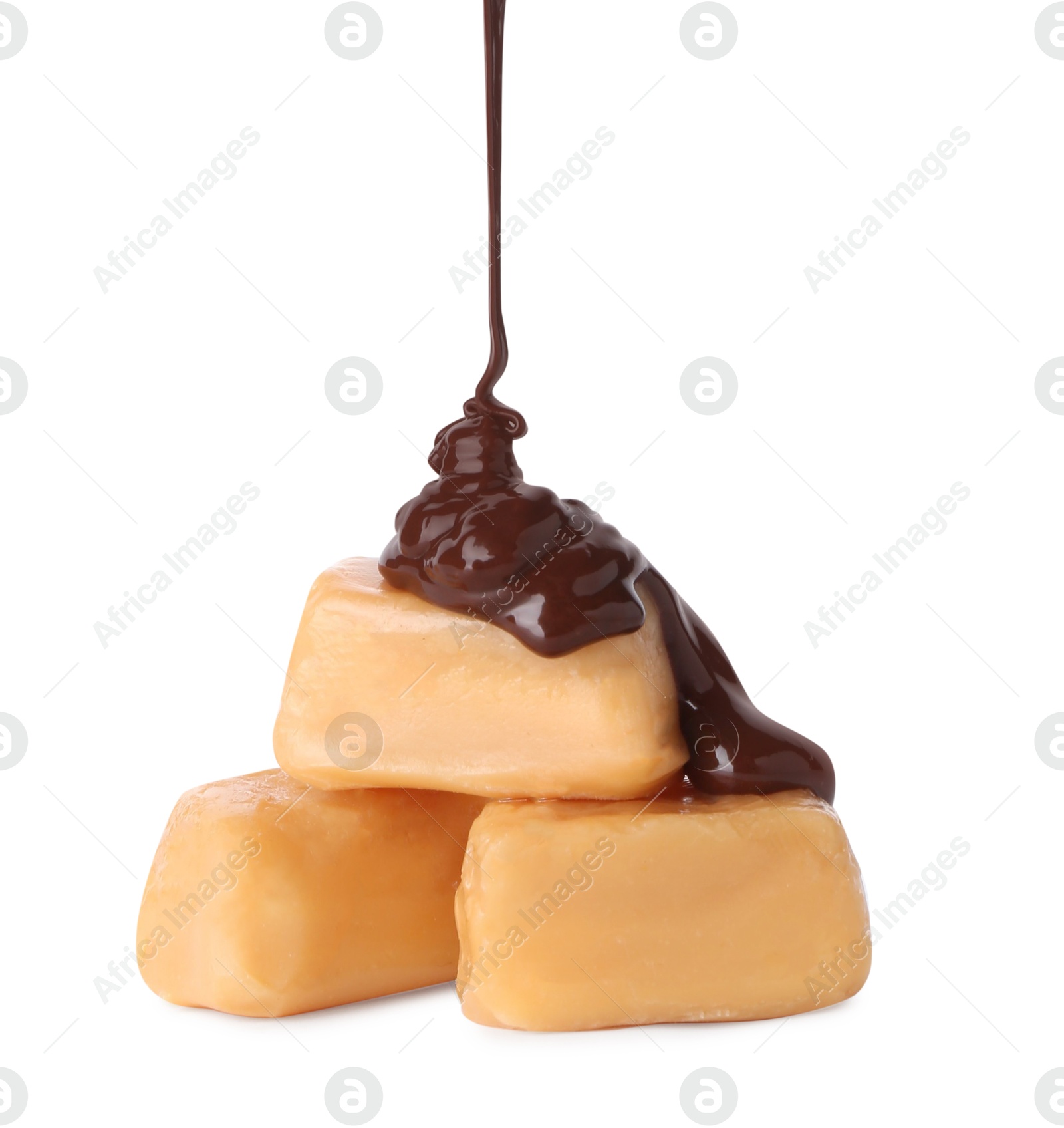 Photo of Pouring delicious melted chocolate onto caramel candies isolated on white