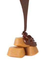 Photo of Pouring delicious melted chocolate onto caramel candies isolated on white