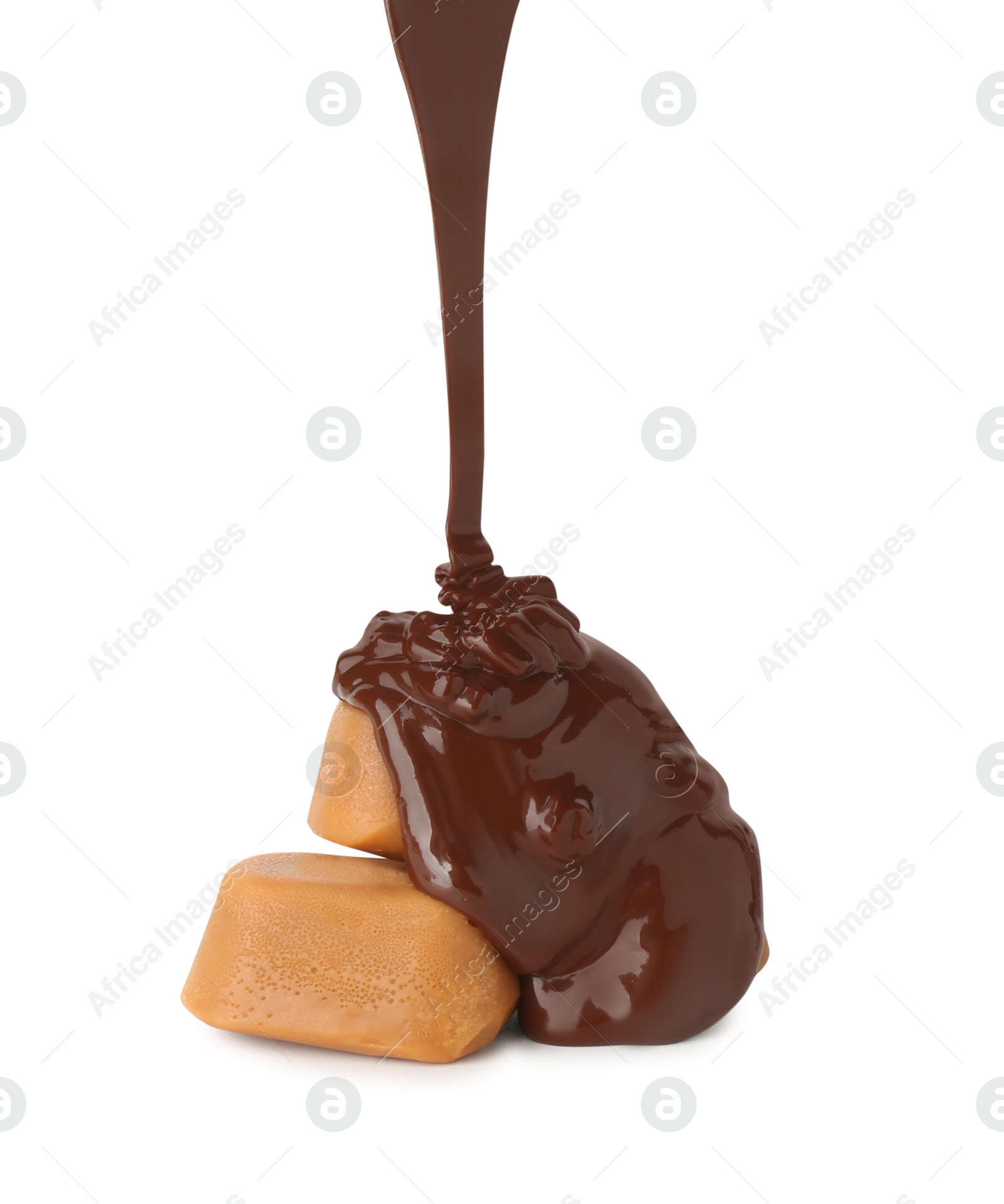 Photo of Pouring delicious melted chocolate onto caramel candies isolated on white