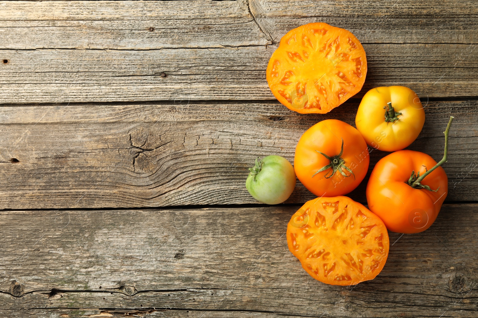 Photo of Whole and cut tomatoes on wooden table, top view. Space for text