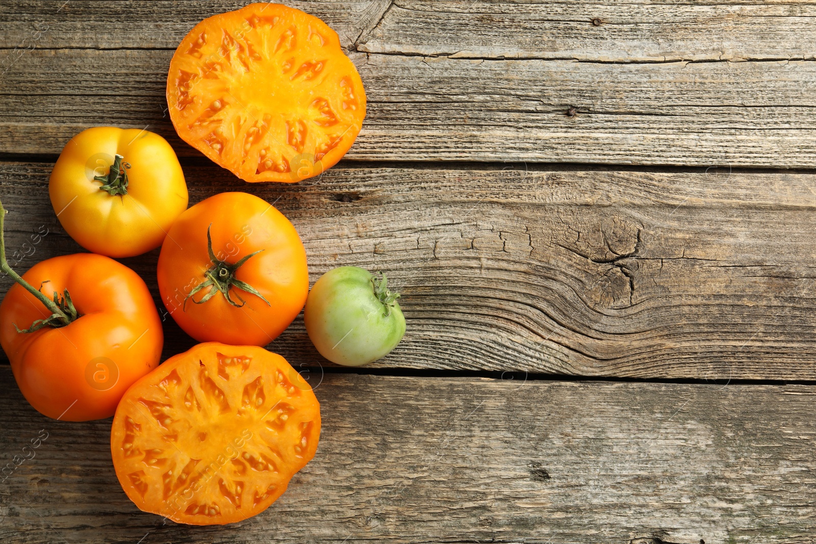 Photo of Whole and cut tomatoes on wooden table, top view. Space for text