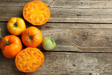 Whole and cut tomatoes on wooden table, top view. Space for text