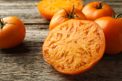 Cut and whole ripe yellow tomatoes on wooden table, closeup