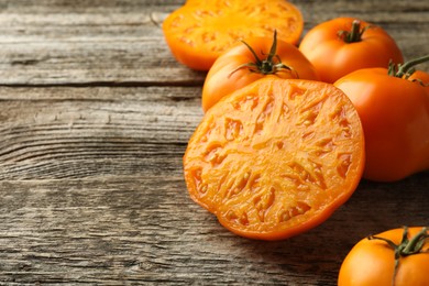 Cut and whole ripe yellow tomatoes on wooden table, closeup. Space for text