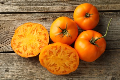 Cut and whole ripe yellow tomatoes on wooden table, top view