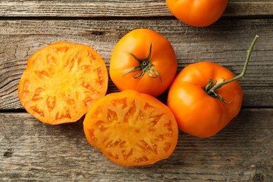 Cut and whole ripe yellow tomatoes on wooden table, top view