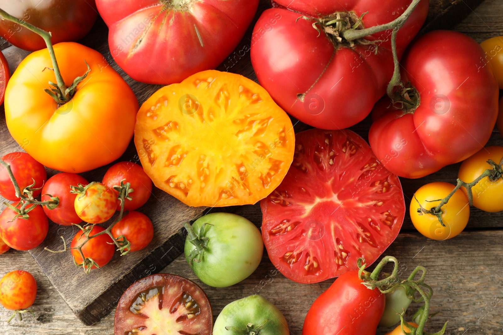 Photo of Different ripe tomatoes on wooden table, top view