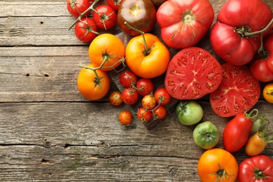 Photo of Different ripe tomatoes on wooden table, top view. Space for text