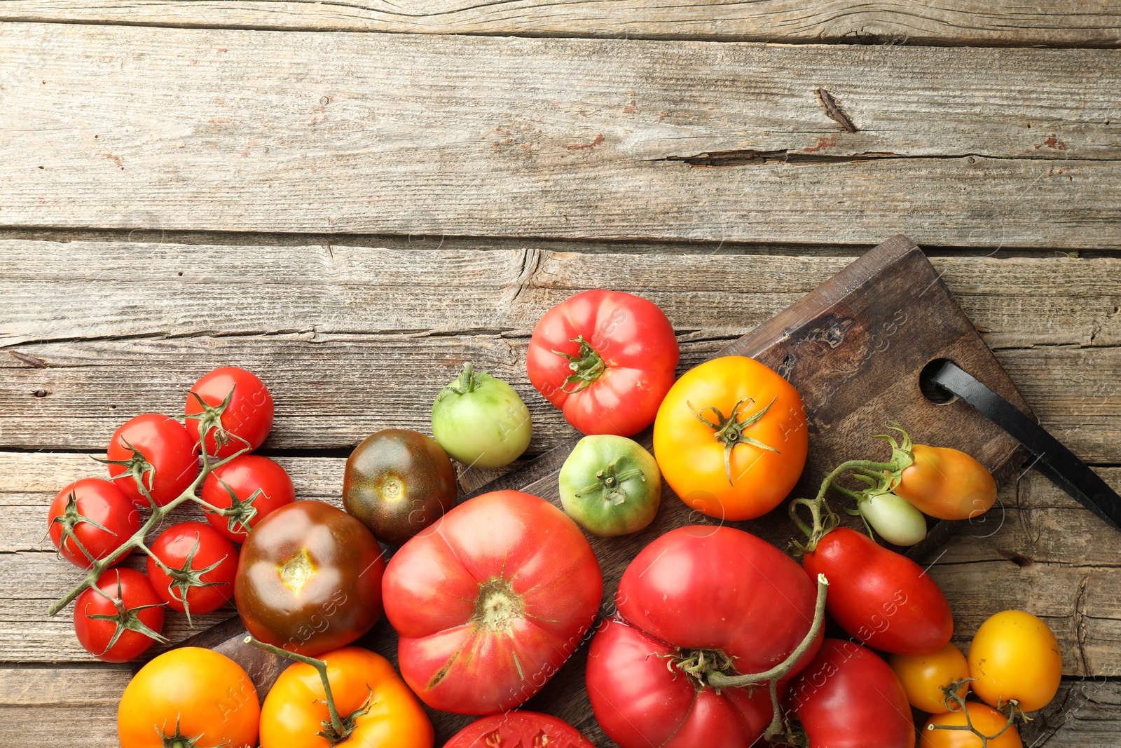 Photo of Different ripe tomatoes on wooden table, top view. Space for text