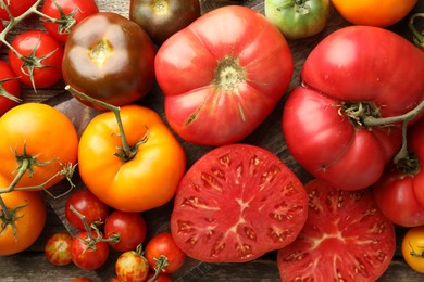 Photo of Different ripe tomatoes on wooden table, top view