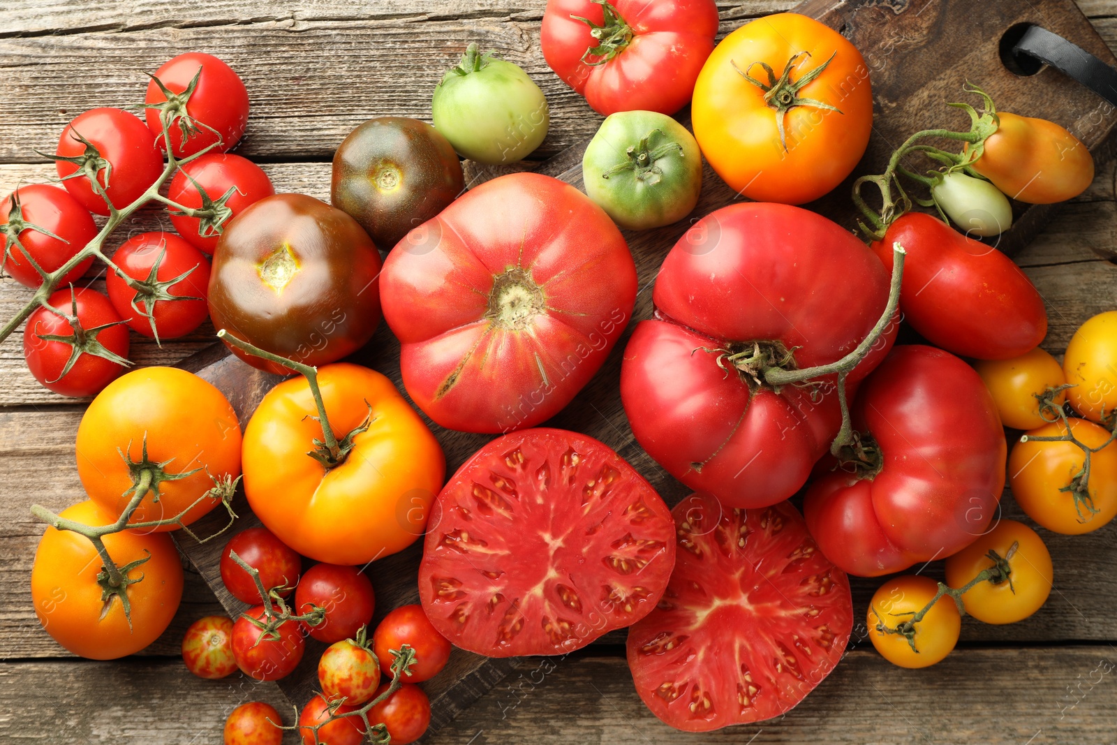 Photo of Different ripe tomatoes on wooden table, top view