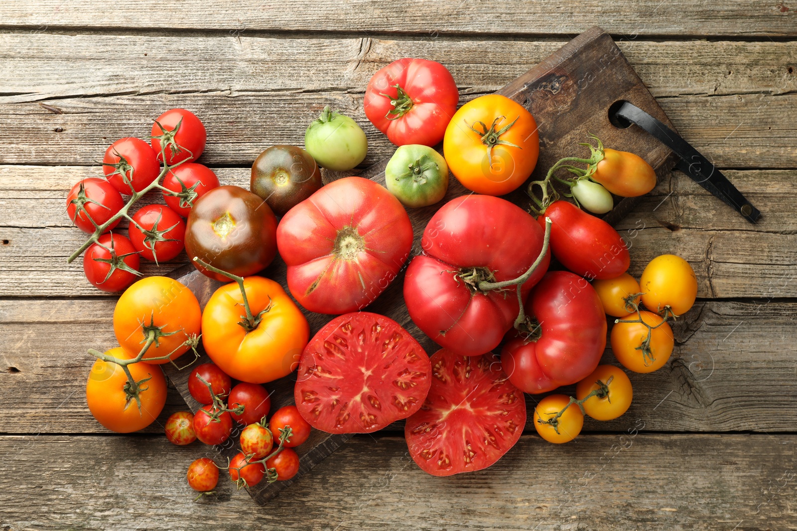 Photo of Different ripe tomatoes on wooden table, top view