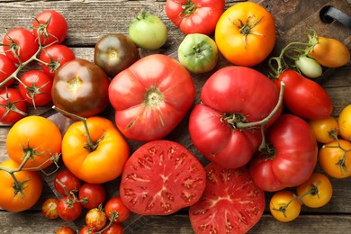 Photo of Different ripe tomatoes on wooden table, top view