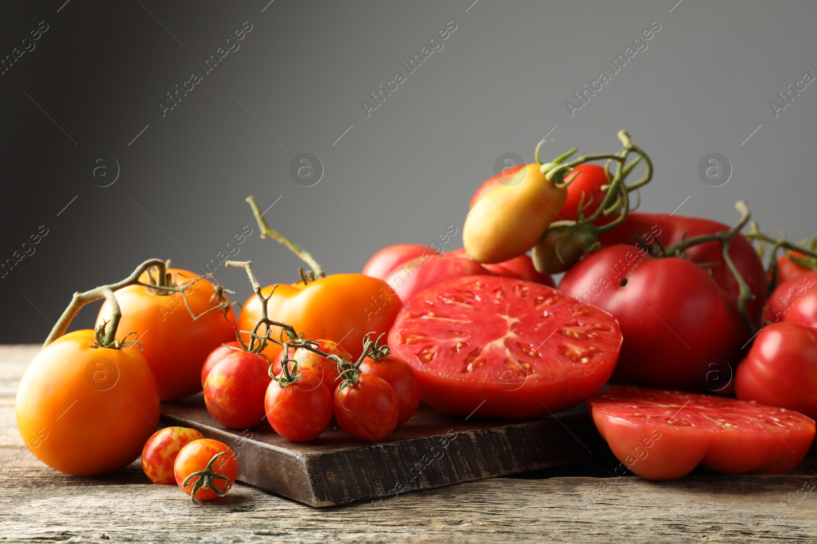 Photo of Many different ripe tomatoes on wooden table