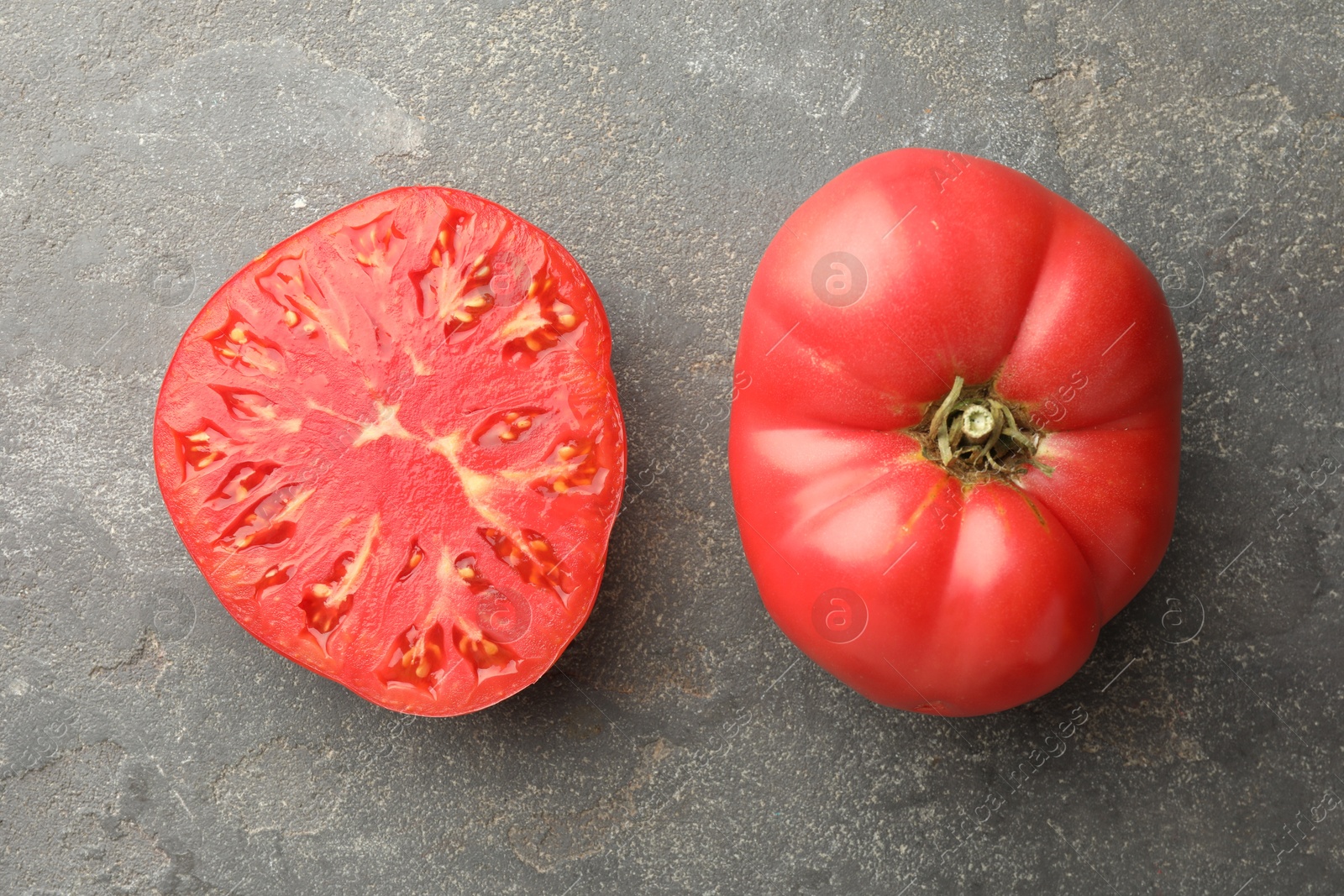 Photo of Whole and cut ripe red tomatoes on grey table, top view