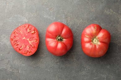 Photo of Whole and cut ripe red tomatoes on grey table, top view