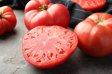 Whole and cut ripe red tomatoes on grey table, closeup