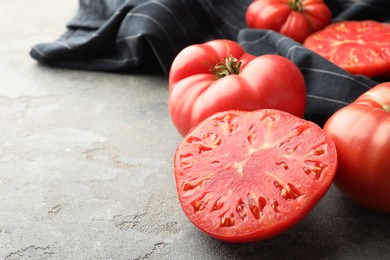 Photo of Whole and cut ripe red tomatoes on grey table, closeup. Space for text