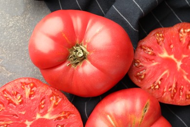 Photo of Whole and cut ripe red tomatoes on grey table, closeup