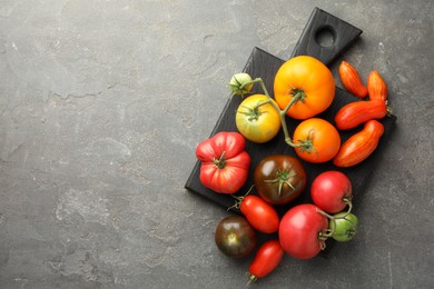 Different ripe tomatoes on grey table, top view. Space for text