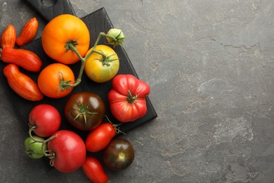 Different ripe tomatoes on grey table, top view. Space for text