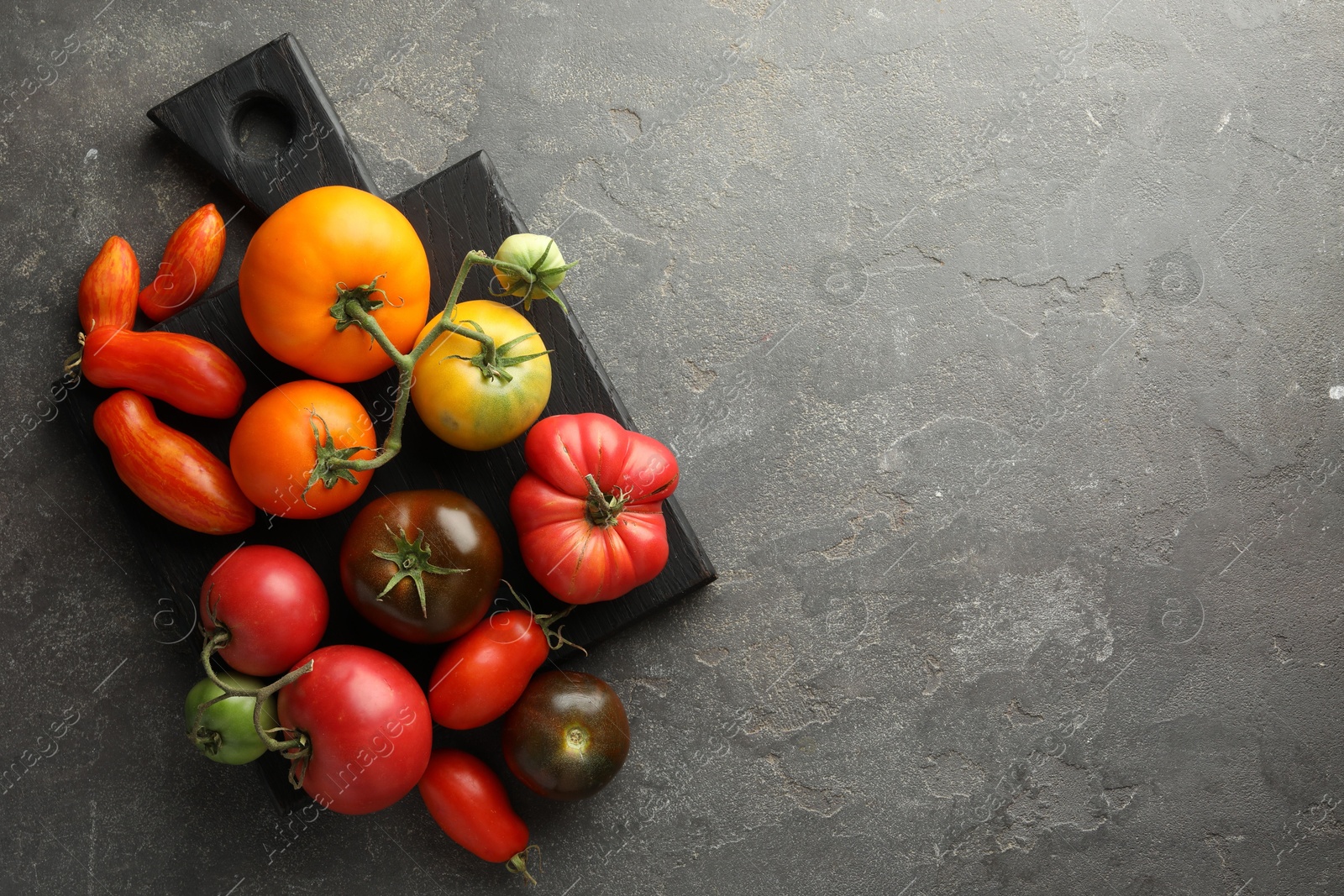 Photo of Different ripe tomatoes on grey table, top view. Space for text