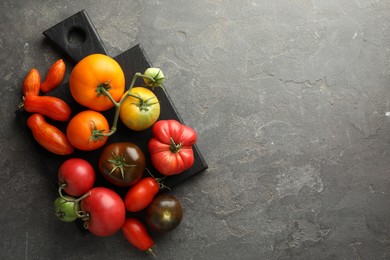 Different ripe tomatoes on grey table, top view. Space for text