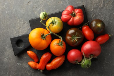 Different ripe tomatoes on grey table, top view