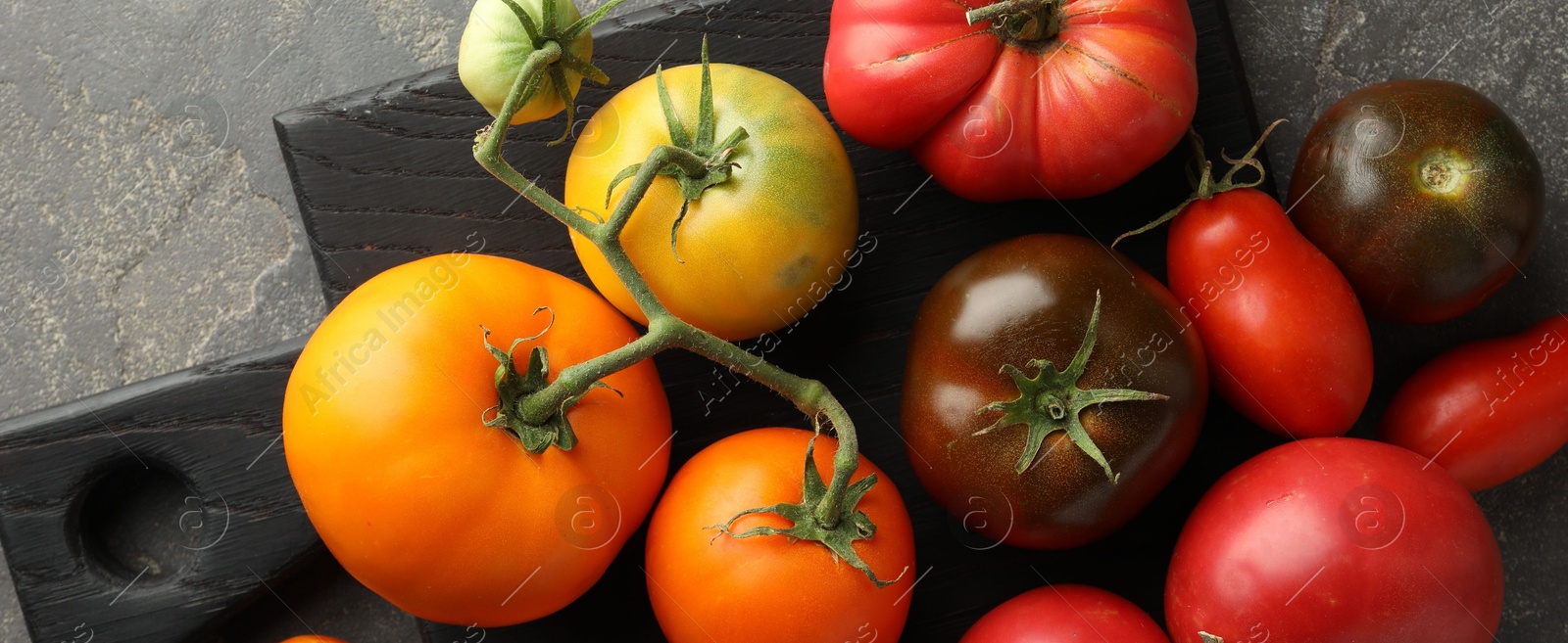 Photo of Different ripe tomatoes on grey table, top view