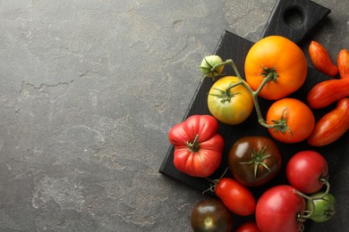 Photo of Different ripe tomatoes on grey table, top view. Space for text