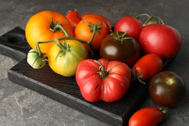 Photo of Different ripe tomatoes on grey table, closeup