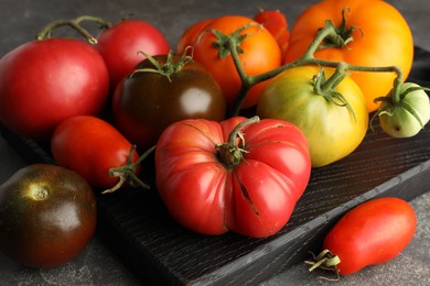 Different ripe tomatoes on grey table, closeup