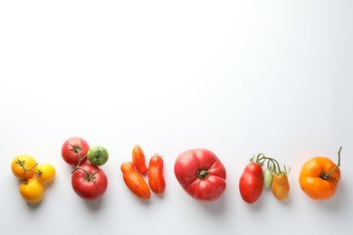 Photo of Different ripe tomatoes on white background, top view. Space for text