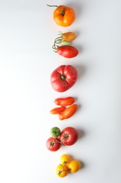 Different ripe tomatoes on white background, flat lay