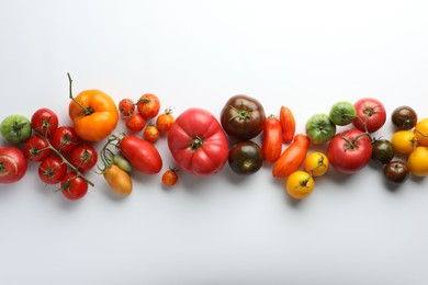 Different ripe tomatoes on white background, flat lay