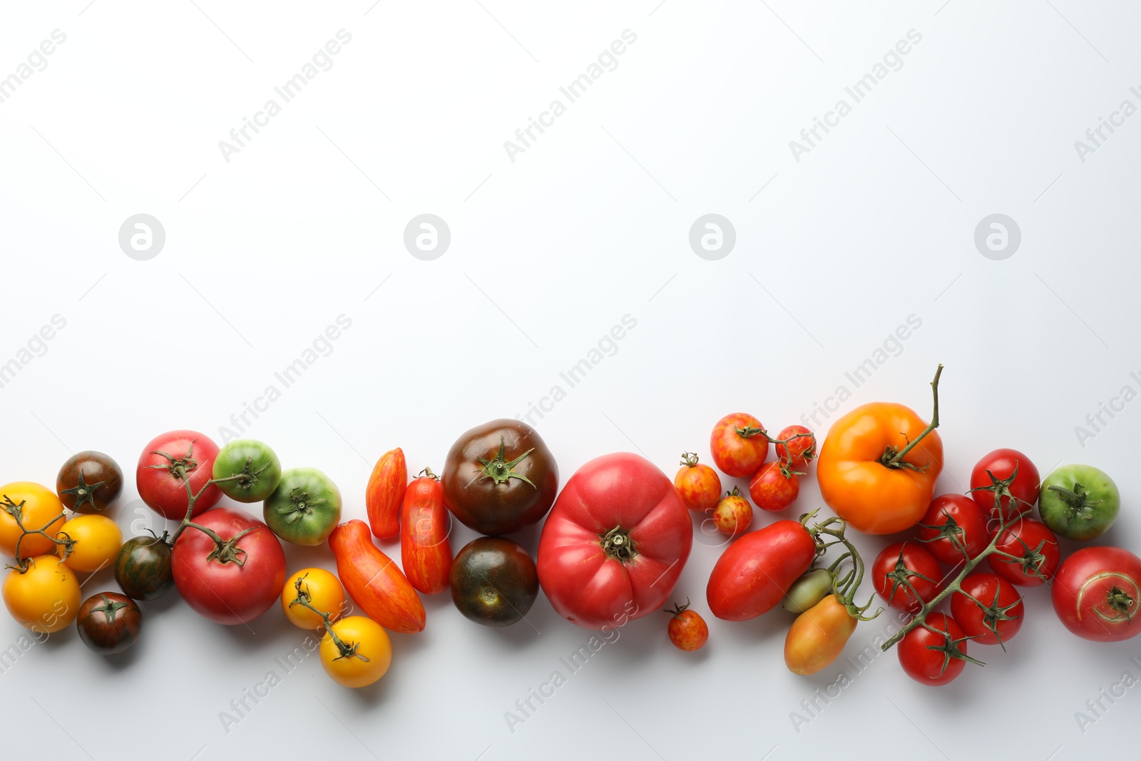 Photo of Different ripe tomatoes on white background, top view. Space for text