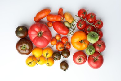 Different ripe tomatoes on white background, flat lay