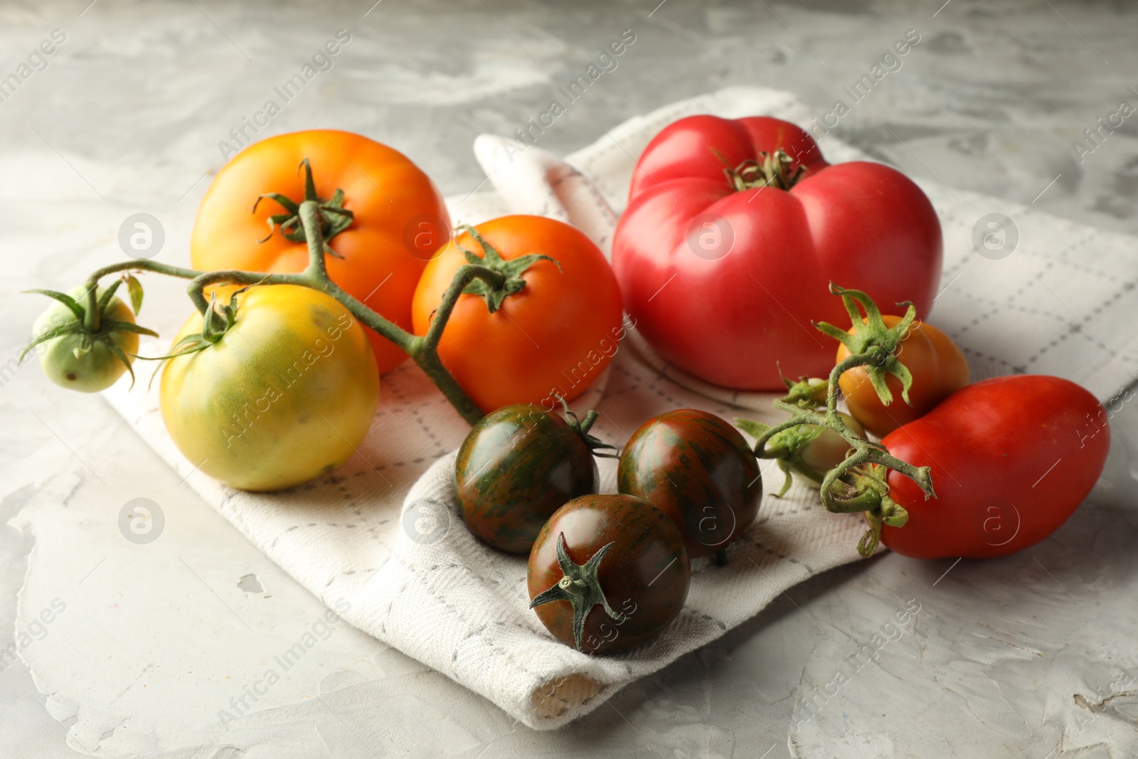 Photo of Different ripe tomatoes on grey textured table